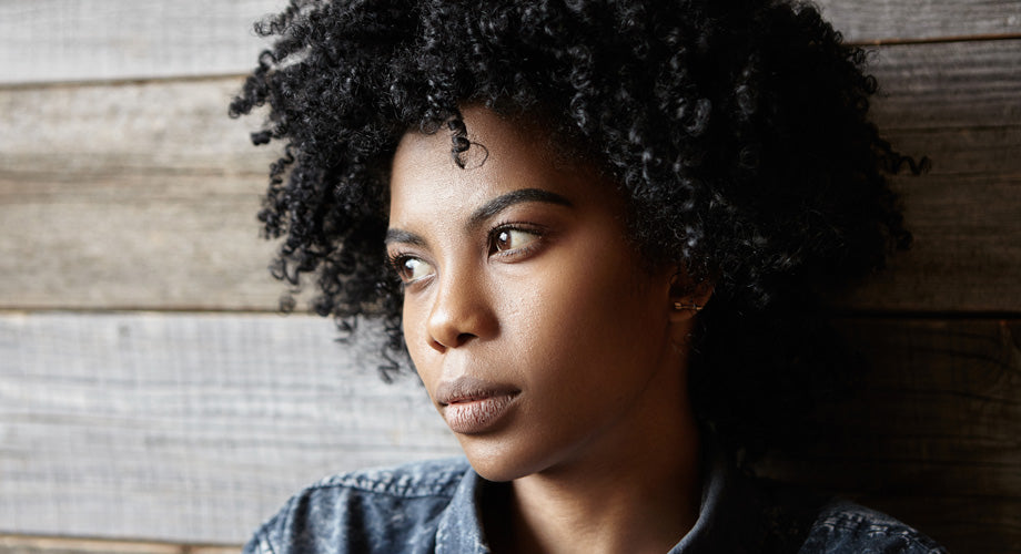 Woman with black curly hair looking off into the distance