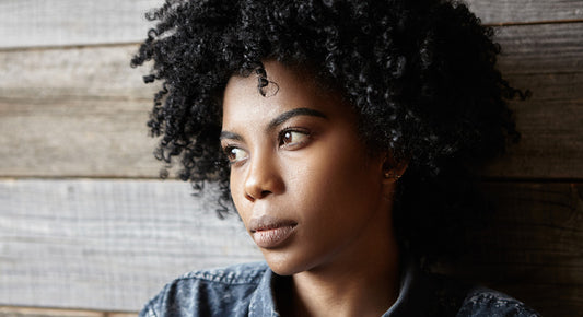 Woman with black curly hair looking off into the distance